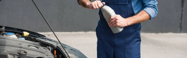 Cropped view of mechanic holding motor oil near car, banner — Stock Photo