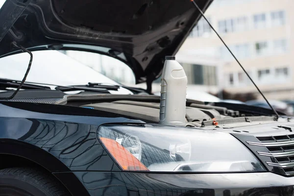 Flasche Motoröl auf Auto mit offener Motorhaube im Freien — Stockfoto