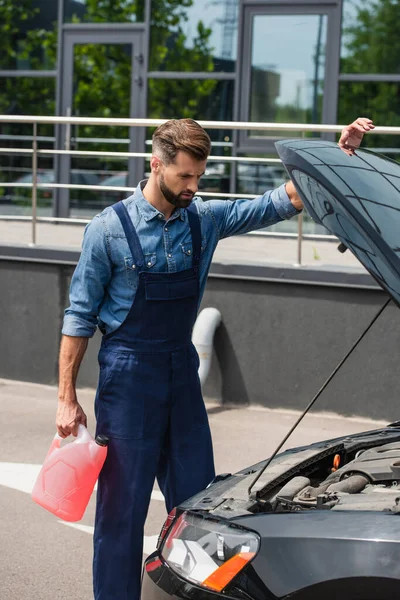 Mechaniker hält Scheibenwaschflüssigkeit in der Nähe des Autos im Freien — Stockfoto