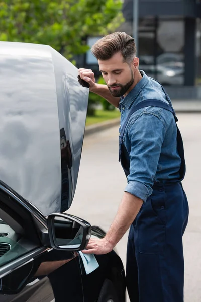 Mécanicien en salopette essuyant voiture à l'extérieur — Photo de stock