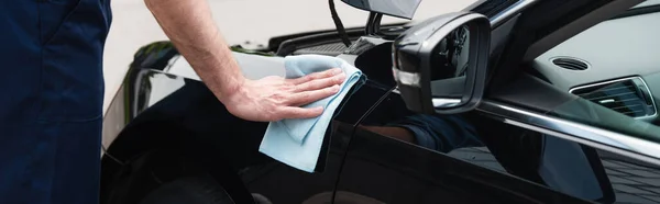 Cropped view of mechanic cleaning car with rag, banner — Stock Photo
