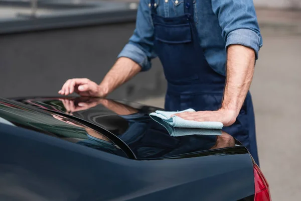 Cropped view of mechanic with rag waxing car outdoors — Stock Photo