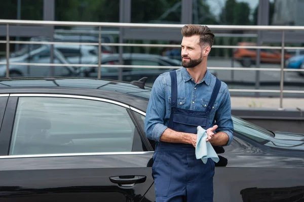 Mechaniker in Overalls hält Lappen in der Nähe von Auto im Freien — Stockfoto