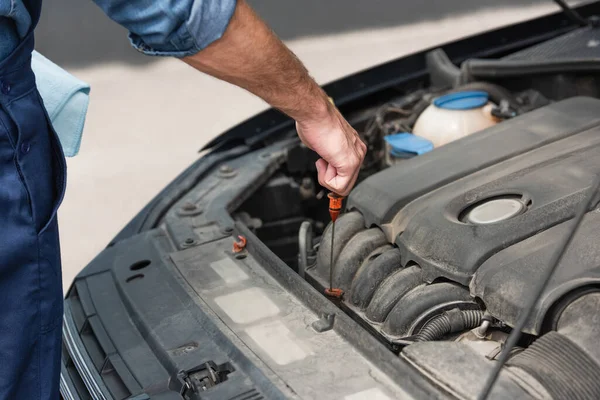 Cropped view of mechanic checking oil in motor of car — Stock Photo