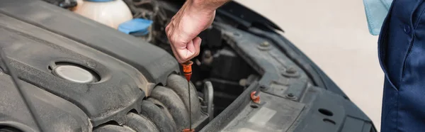 Cropped view of mechanic with dipstick checking motor oil, banner — Stock Photo