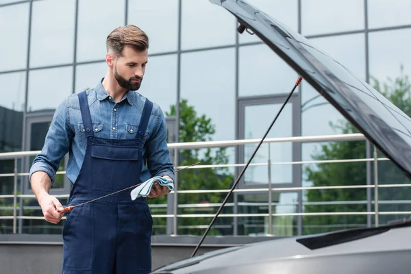 Mécanicien avec jauge et chiffon regardant la voiture à l'extérieur — Photo de stock