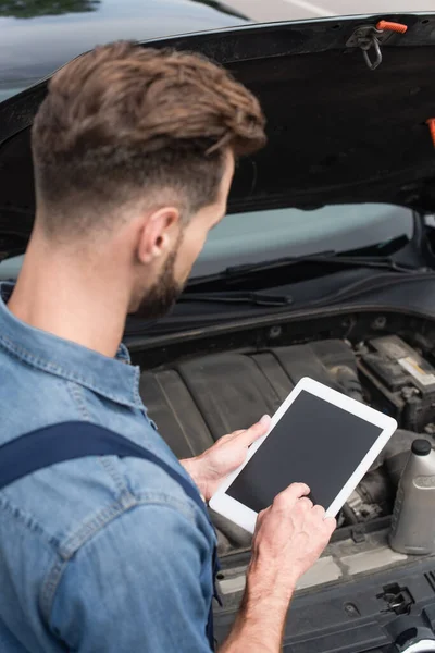 Vue grand angle de la tablette numérique dans les mains du mécanicien près de la voiture à l'extérieur — Photo de stock