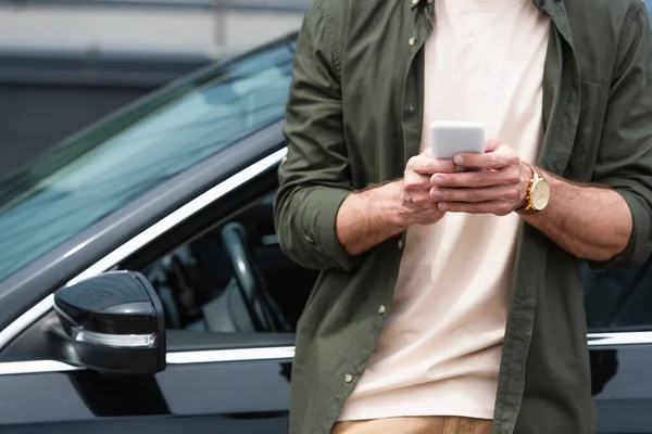 Vue recadrée de l'homme en utilisant un smartphone près de la voiture — Photo de stock