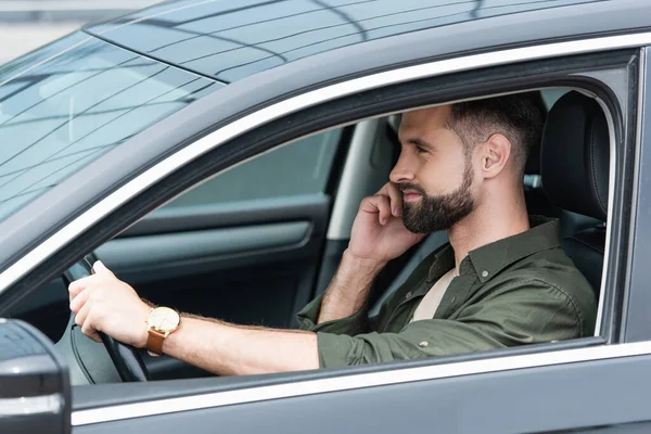 Vista lateral do homem falando no celular enquanto dirige o carro — Fotografia de Stock