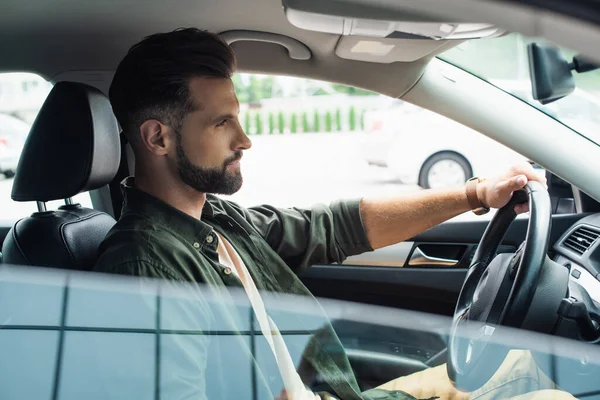 Vue latérale du jeune homme barbu conduisant une voiture à l'extérieur — Photo de stock