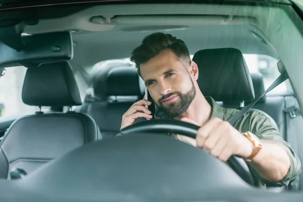 Bearded driver talking on smartphone in auto — Stock Photo