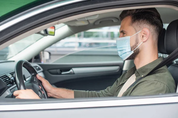 Side view of man in medical mask driving car — Stock Photo