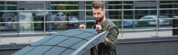 Young man opening hood of car outdoors, banner — Stock Photo