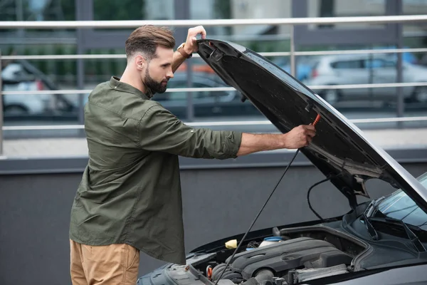 Side view of man opening hood of auto outdoors — Stock Photo