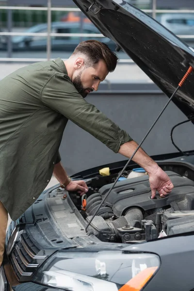 Side view of man opening cap of motor in car outdoors — Stock Photo