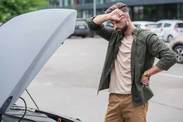 Conductor disgustado mirando el coche con capucha abierta al aire libre - foto de stock