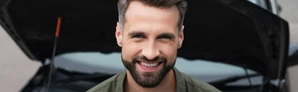 Sorrindo homem olhando para a câmera perto de carro borrado, banner — Fotografia de Stock