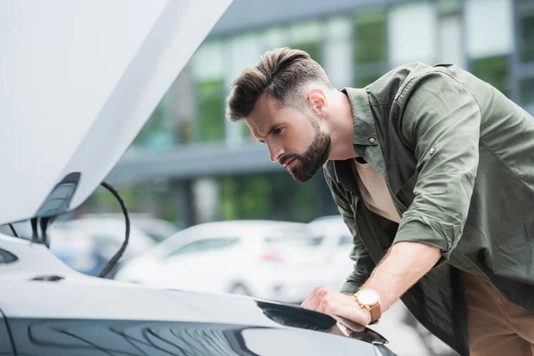 Side view of focused man looking at car with open hood — Stock Photo