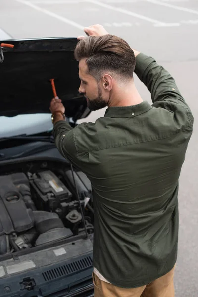 Hochwinkelaufnahme des Fahrers, der die Motorhaube des Autos auf verschwommenem Hintergrund öffnet — Stockfoto