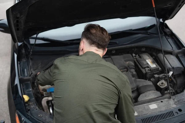 Back view of driver standing near car with open hood — Stock Photo