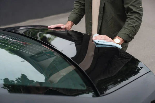 Vista cortada do homem segurando pano enquanto limpa o tronco do carro — Fotografia de Stock