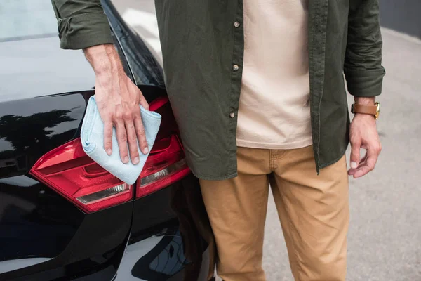 Cropped view of driver cleaning turn signal of auto — Stock Photo