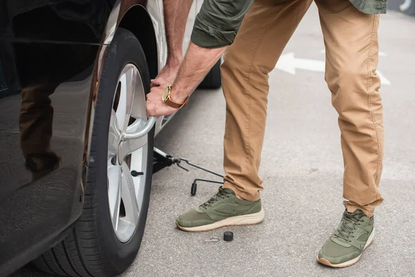 Cropped view of man using wheel wrench on car outdoors — Stock Photo