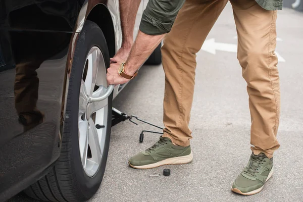 Vue recadrée de l'homme utilisant la clé à molette sur la voiture à l'extérieur — Photo de stock