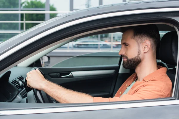 Vista lateral del hombre barbudo conduciendo coche - foto de stock