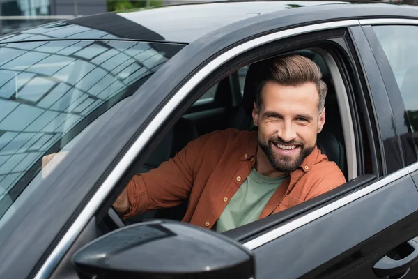 Lächelnder Fahrer blickt im Auto in Kamera — Stockfoto
