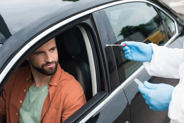 Medical worker holding cotton swab of pcr test near driver in car — Stock Photo