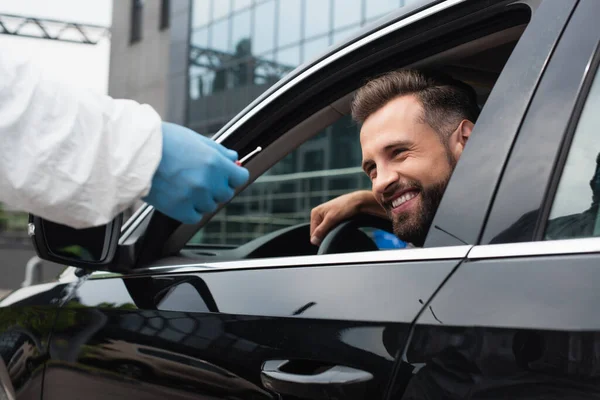 Lächelnder Fahrer im Auto in der Nähe medizinischer Mitarbeiter mit PCR-Test — Stockfoto