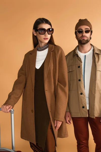 Paar Touristen im trendigen Herbst-Outfit in der Nähe von Koffer isoliert auf beige — Stockfoto