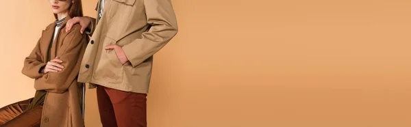 Cropped view of man in jacket near stylish woman sitting with crossed arms isolated on beige, banner — Foto stock