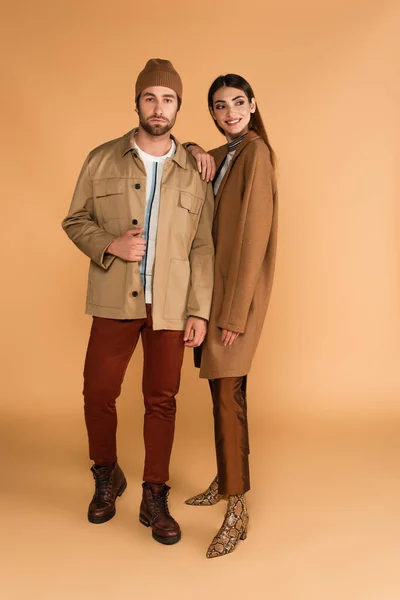 Smiling woman leaning on shoulder of man in trendy autumn clothes on beige background — Fotografia de Stock