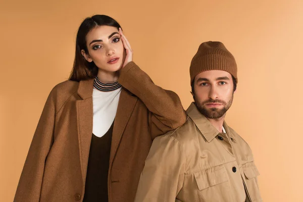 Young couple in stylish autumn outfit looking at camera isolated on beige — Foto stock