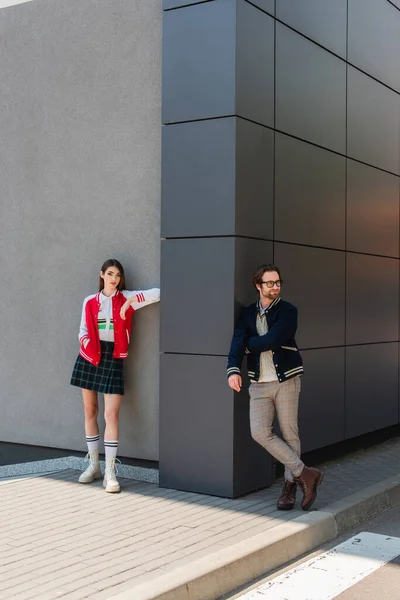 Full length view of fashionable young couple standing near grey building on city street — Foto stock