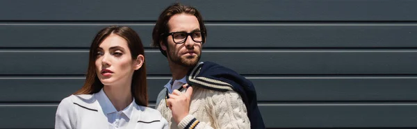 Man in eyeglasses standing near grey wall near young stylish woman, banner — Stock Photo