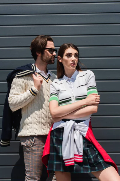 Young couple in fashionable clothes looking away while posing outdoors — Foto stock