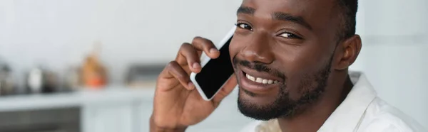 Hombre americano africano alegre que habla en el teléfono inteligente, bandera - foto de stock