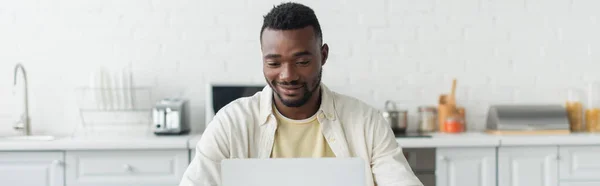 Freelancer afroamericano feliz usando el ordenador portátil, bandera - foto de stock