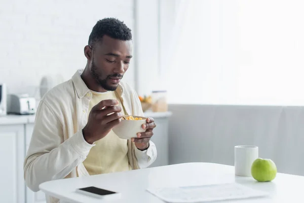 African american man holding bowl while having breakfast — Stock Photo