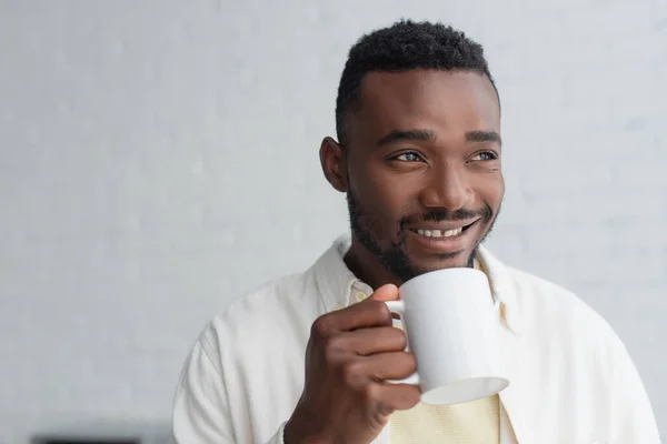 Heureux homme afro-américain tenant tasse de café le matin — Photo de stock