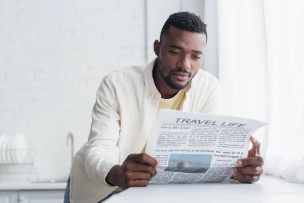 Африканский американец в футболке, читающий туристическую газету — стоковое фото