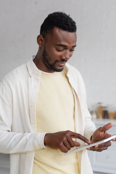 Улыбающийся африканский американец, использующий цифровой планшет дома — стоковое фото