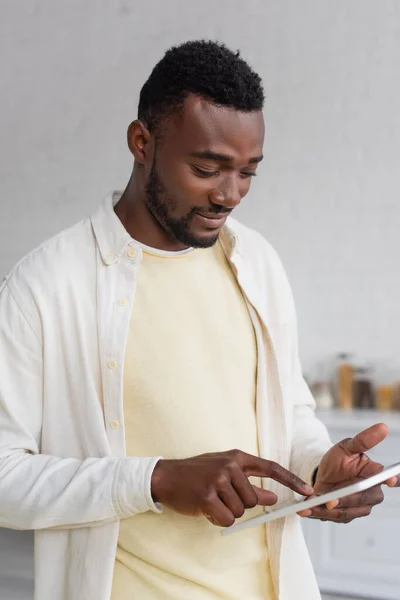 Uomo afroamericano sorridente utilizzando tablet digitale a casa — Foto stock