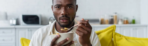 Junger afrikanisch-amerikanischer Mann hält Schüssel mit Cornflakes und Löffel, Banner — Stockfoto