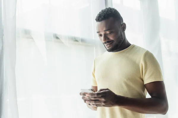 Happy african american man messaging on smartphone — Stock Photo