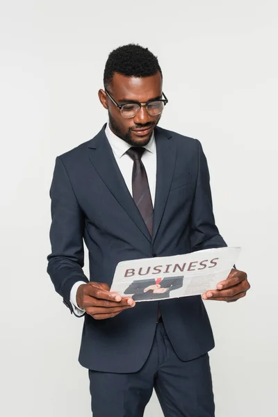 Afro-américain dans les lunettes lecture journal d'affaires isolé sur gris — Photo de stock