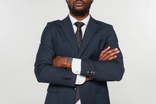 Vista recortada del hombre afroamericano en traje de pie con brazos cruzados aislados en gris - foto de stock